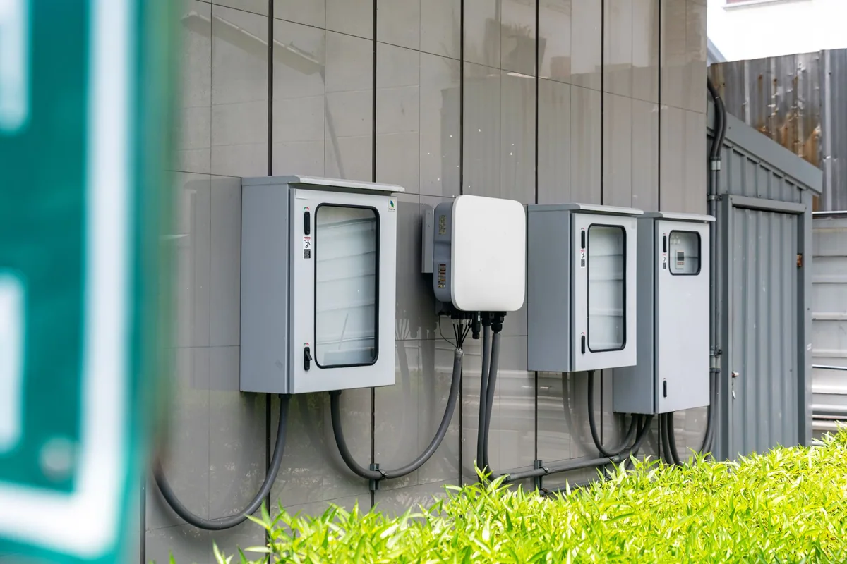 Inversor de una instalación solar entre armarios eléctricos, con sus tubos de cable, en la pared exterior de un edificio