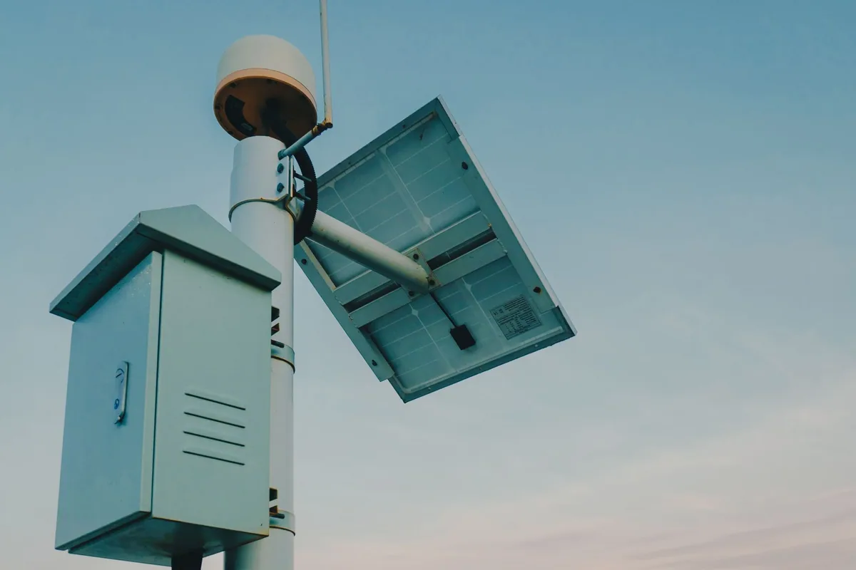 Parte trasera de un pequeño panel solar montado en un poste, con su caja de conexiones y la etiqueta de datos técnicos