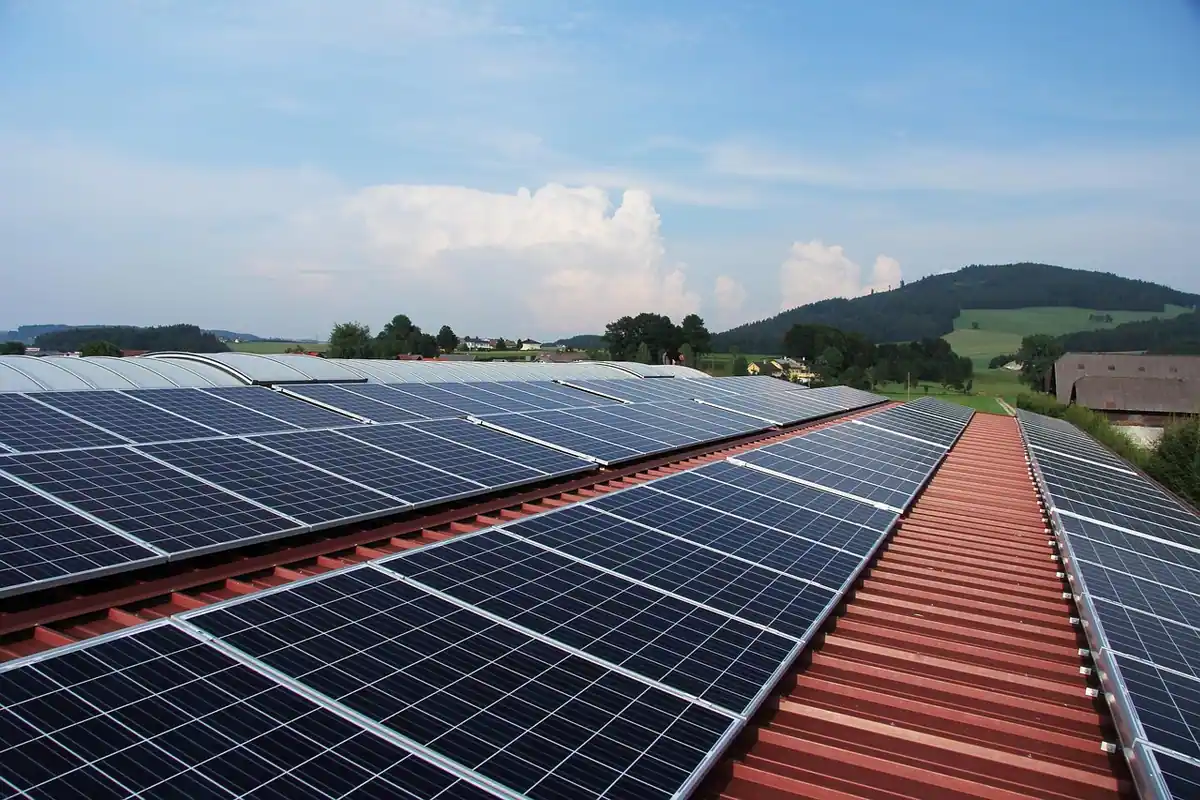 Placas solares en filas sobre la cubierta de chapa de una nave, a ambos lados de la cumbrera