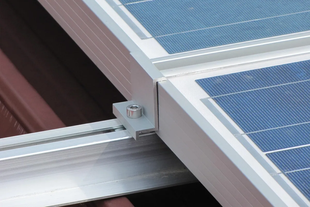 Perfil de aluminio y grapa que sujetan dos placas solares a la estructura de la cubierta
