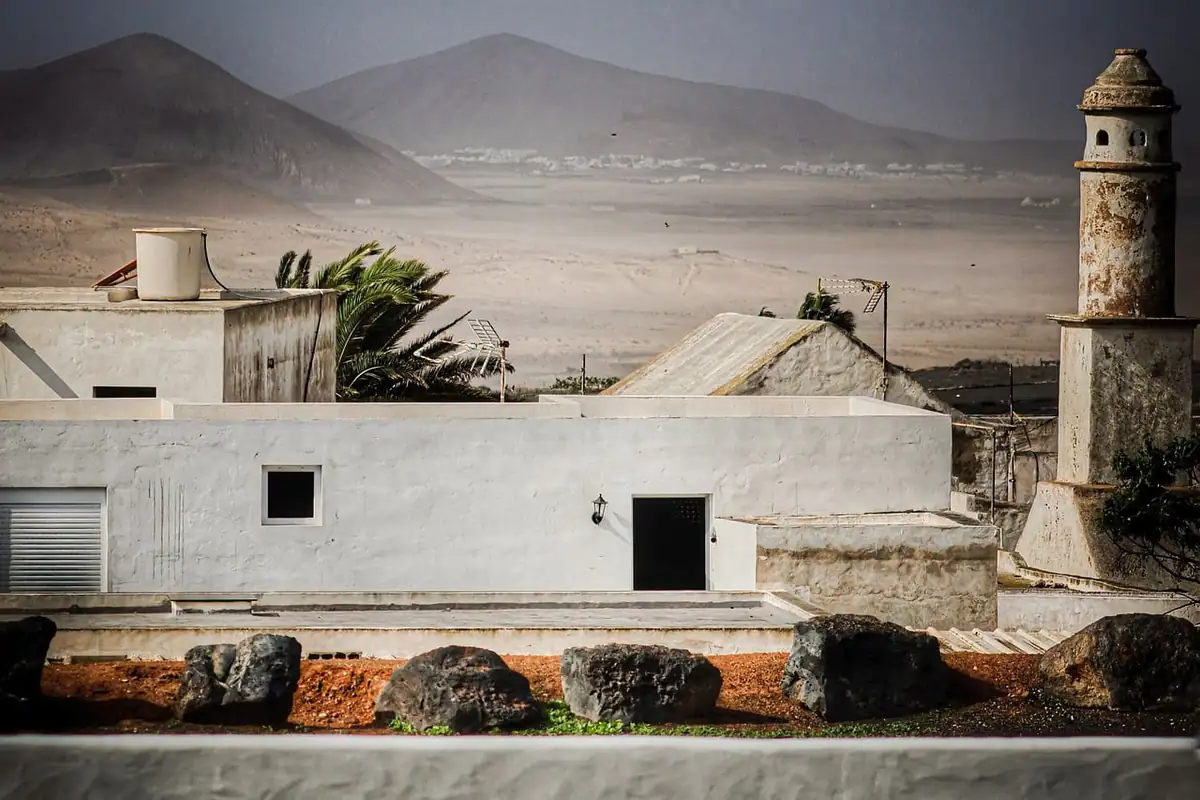 Casas blancas de azotea plana con un depósito de agua en el techo y montañas secas al fondo