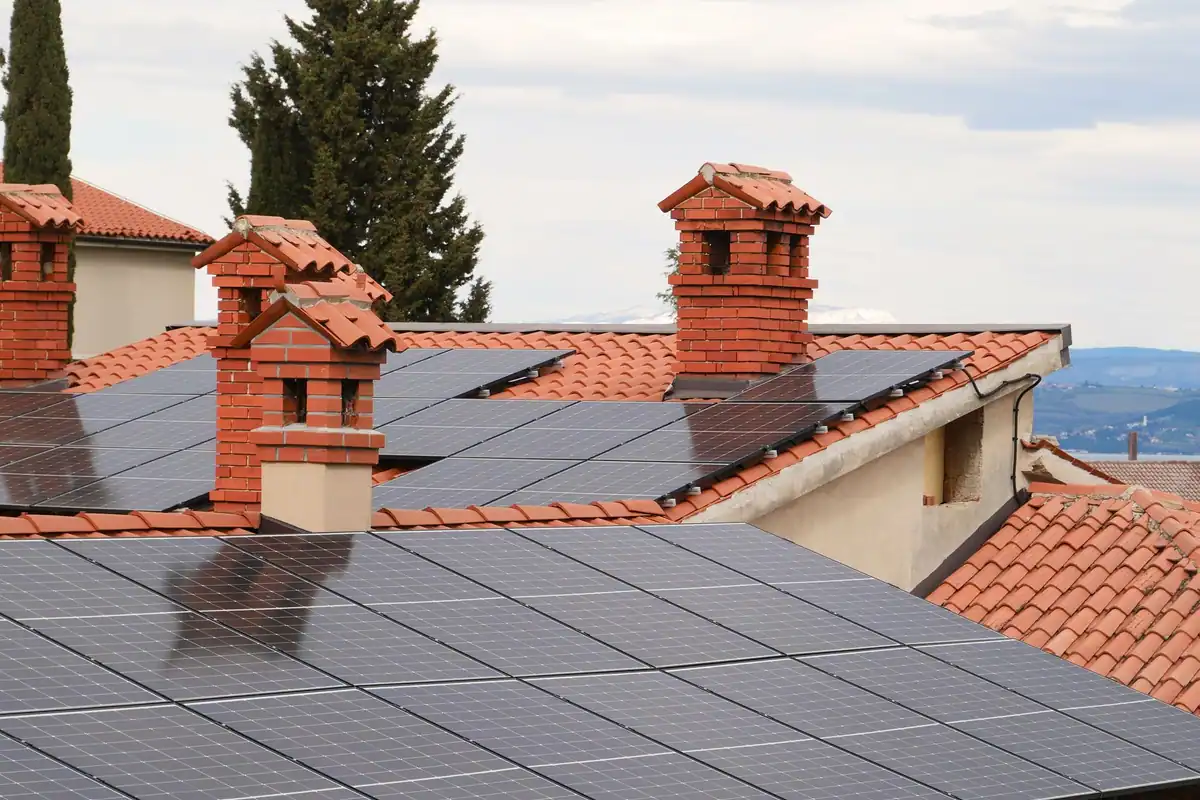 Tejados de teja cubiertos de placas solares entre chimeneas de ladrillo